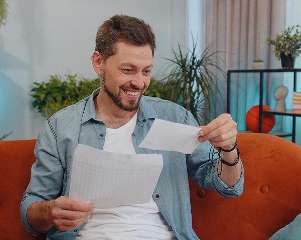 Smiling man holding energy bill with solar panels