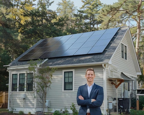 Man reviewing documents in front of house with solar panels
